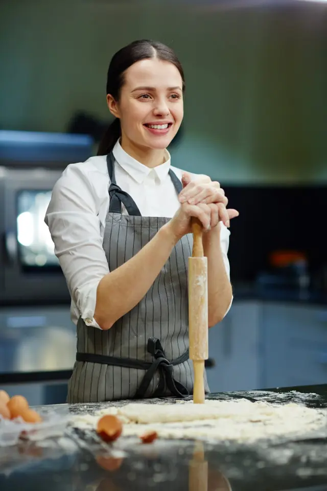 A smiling pastry chef with a rolling pin